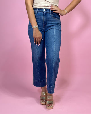 Person wearing blue jeans on a pink background