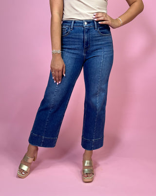 Person wearing blue jeans on a pink background