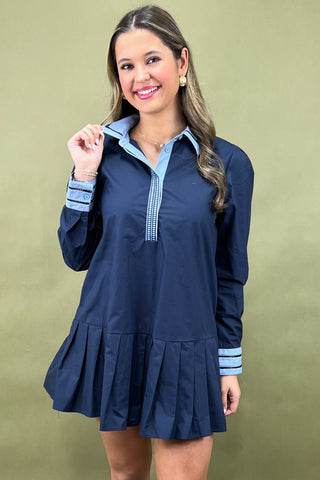 Woman wearing a navy dress with blue trim against a beige background