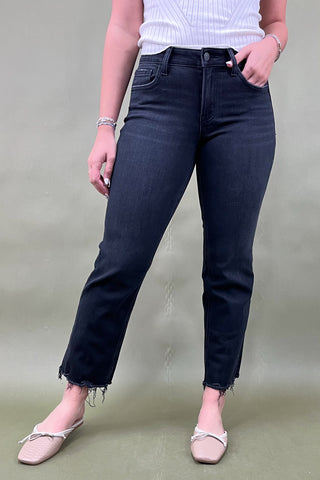 Person wearing black jeans and a white top on a plain background