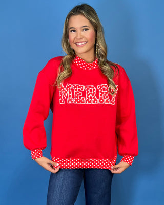 Red Merry graphic sweatshirt with white polka dot lettering, coordinating polka dot mock neckline, cuffs and hem, long sleeves, and a relaxed fit.
