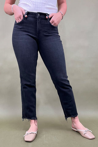 Person wearing black jeans and a white top against a plain background