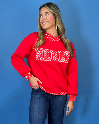Red Merry graphic sweatshirt with white polka dot lettering, coordinating polka dot mock neckline, cuffs and hem, long sleeves, and a relaxed fit.