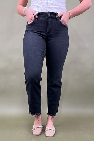 Person wearing black jeans and a white top on a plain background