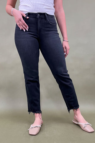 Person wearing black jeans and a white top against a plain background