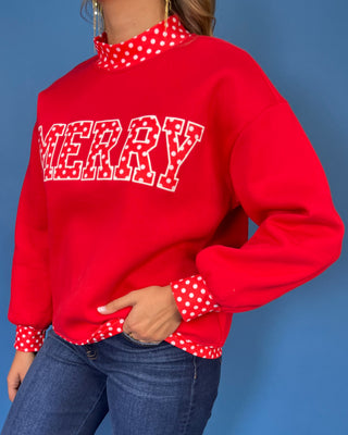 Red Merry graphic sweatshirt with white polka dot lettering, coordinating polka dot mock neckline, cuffs and hem, long sleeves, and a relaxed fit.