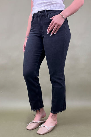 Person wearing black jeans and a white top on a beige background