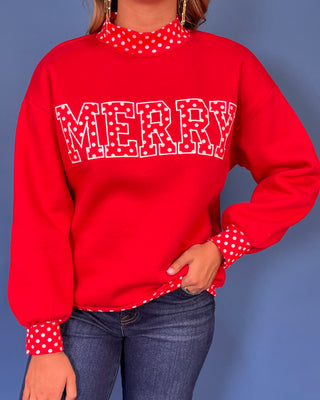 Red Merry graphic sweatshirt with white polka dot lettering, coordinating polka dot mock neckline, cuffs and hem, long sleeves, and a relaxed fit.