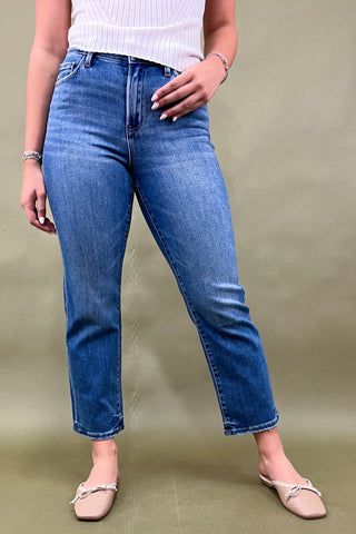 Person wearing blue jeans and a white top on a plain background