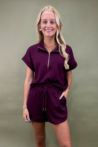 Woman wearing a purple outfit against a plain background