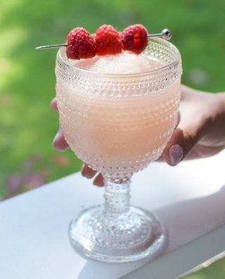 Glass of pink drink with raspberries on a blurred green background
