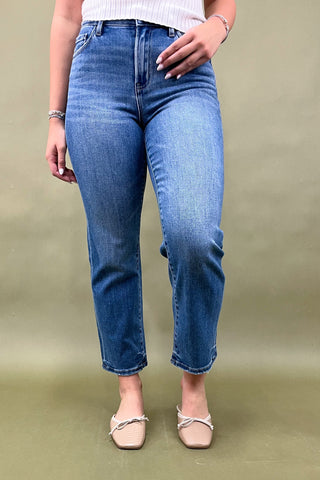 Person wearing blue jeans on a plain background
