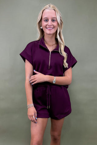 Woman wearing a purple outfit against a plain background