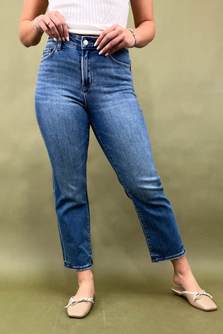 Person wearing blue jeans and a white top on a green background