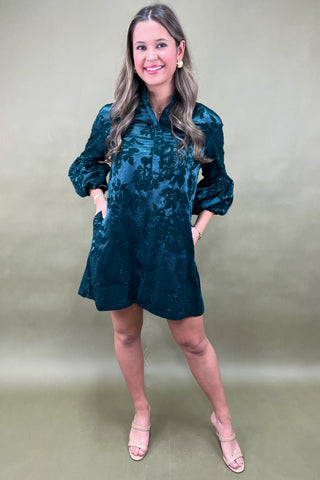 Woman wearing a teal floral dress against a beige background