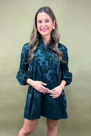 Woman wearing a green floral dress against a beige background