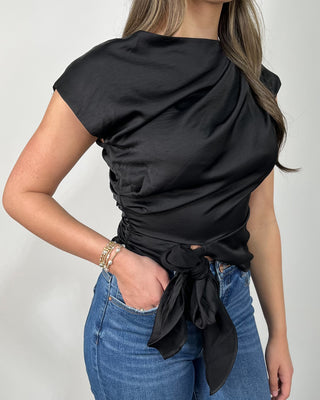 Chic black satin tie-front top with a softly draped neckline, paired with raw-hem flare jeans and nude block heels for that effortlessly elevated look. It’s the perfect mix of sleek + comfortable—easy for date night, dinner plans, or whenever you want to feel a little extra polished.