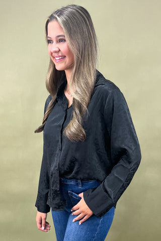 Woman wearing a black shirt and blue jeans against a beige background