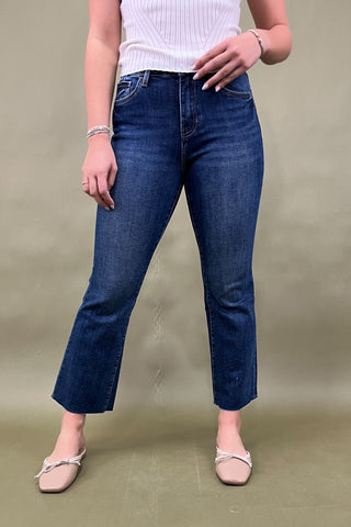 Person wearing blue jeans and a white top on a plain background