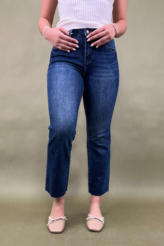 Person wearing blue jeans and a white top on a beige background