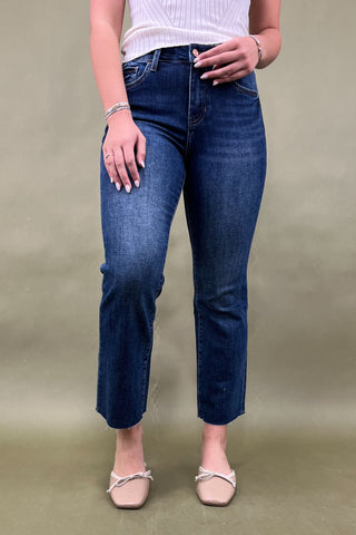 Person wearing blue jeans and a white top on a beige background