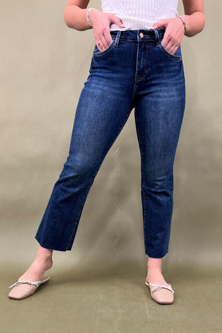 Person wearing blue jeans against a beige background