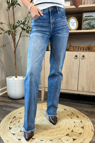 Person wearing blue jeans standing on a round woven rug indoors.