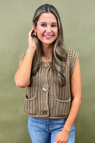 Woman wearing a brown knitted vest against a green background