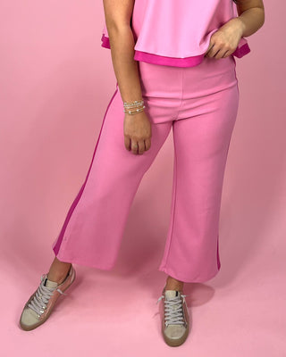 Person wearing a pink outfit with wide-leg pants on a pink background