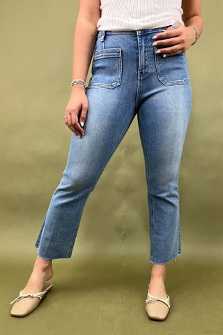 Person wearing blue jeans and a white top on a green background