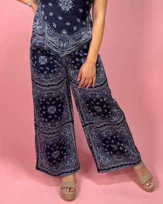 Person wearing a navy blue patterned outfit on a pink background