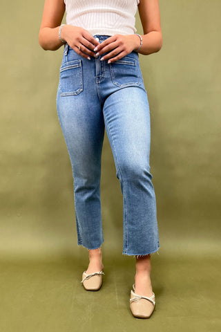 Person wearing light blue jeans and a white top on an olive green background