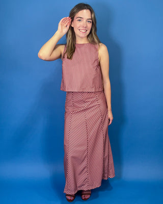 Burgundy and blush striped two-piece set featuring a sleeveless cropped top and coordinating high-waisted maxi skirt with mixed-direction stripe detailing.