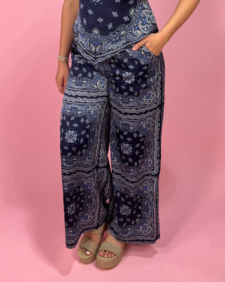 Person wearing blue patterned pants on a pink background