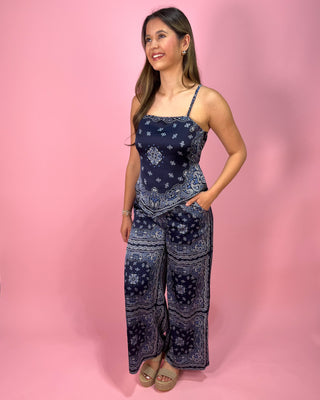 Woman wearing a blue patterned jumpsuit on a pink background