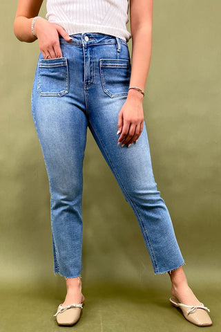 Person wearing blue jeans against a green background