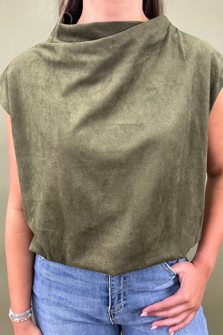 Person wearing a green sleeveless top and blue jeans against a neutral background