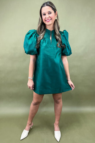 Woman wearing a green dress with puff sleeves against a green background