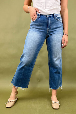 Person wearing blue jeans and a white top on a green background
