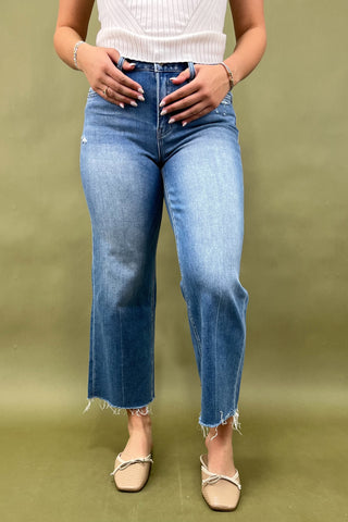 Person wearing blue jeans and a white top on a green background