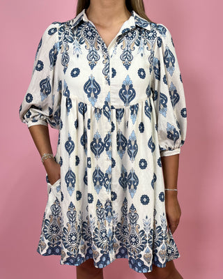 Woman wearing a white dress with blue patterns on a pink background
