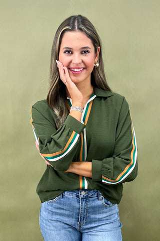Woman wearing a green jacket with colorful stripes on a beige background