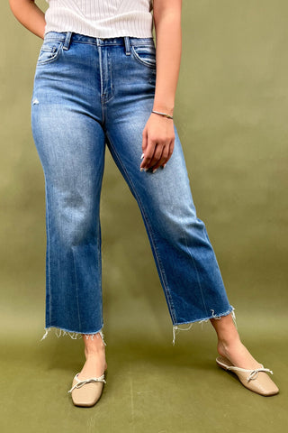 Person wearing blue jeans and beige shoes on a green background