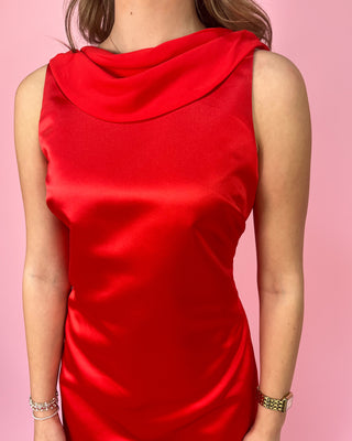 Red sleeveless dress worn by a person on a pink background