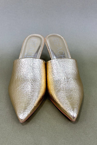 Pair of metallic gold pointed-toe shoes on a gray background