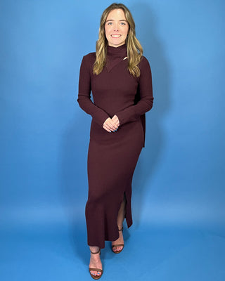 Deep burgundy ribbed knit maxi dress with long sleeves, a fitted silhouette, side slit, and chic asymmetrical cutout mock neckline.