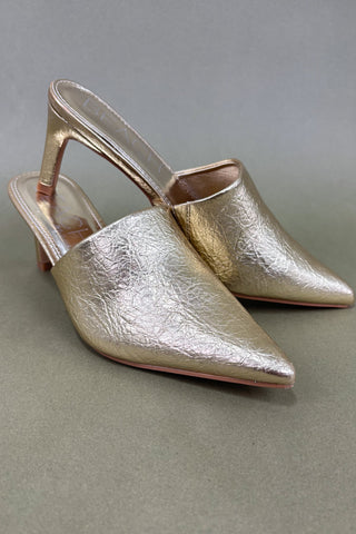 Pair of gold metallic high-heeled shoes on a gray background