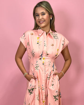 Woman wearing a pink floral dress against a pink background