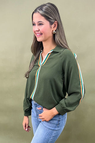 Woman wearing a green blouse with white trim against a beige background