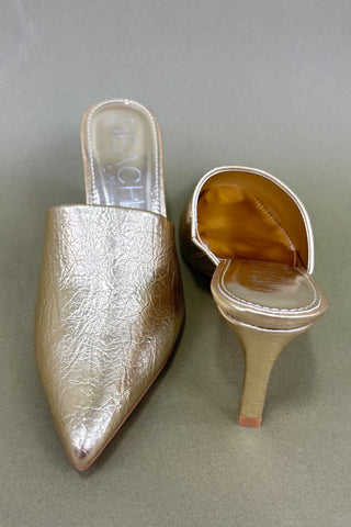 Gold high-heeled shoe on a gray background
